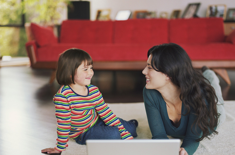 A parent on a laptop with her child.