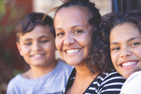 A parent smiling with her two children on either side of her. 