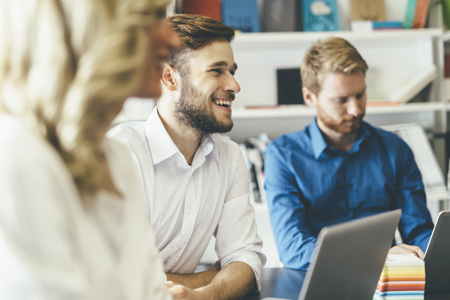 People sitting at a table with laptops open smiling. 