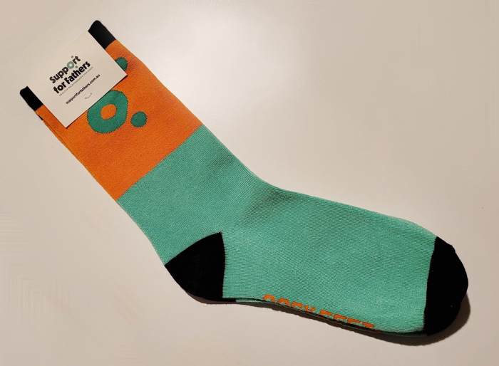 Bright orange and green socks with a Support for Fathers tag attached to the ankle area