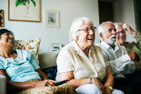 Two laughing couples sitting on a couch.