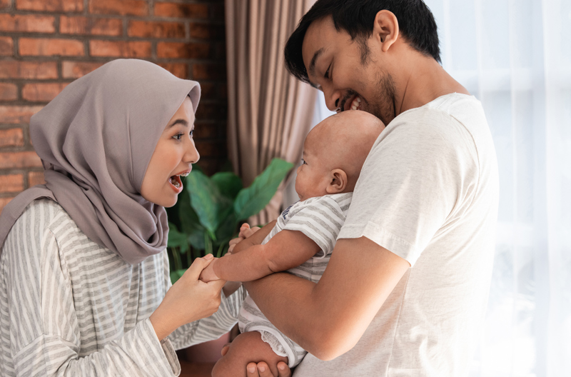 Two parents holding their child smiling at each other.