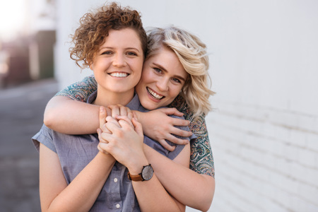 A smiling couple embracing outside.