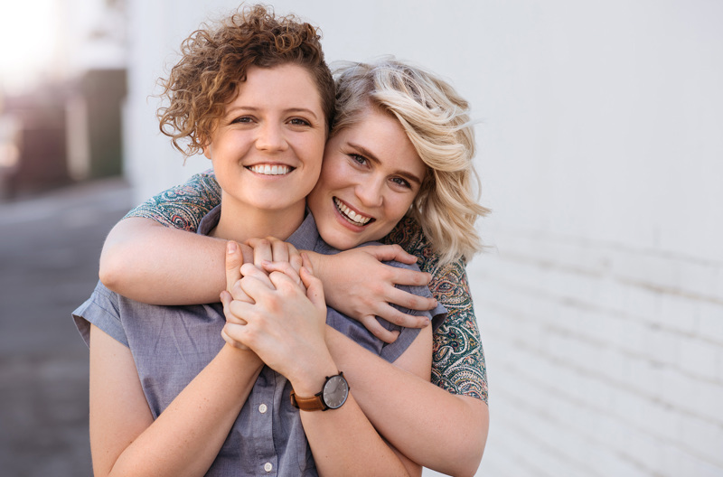 A smiling couple embracing outside.