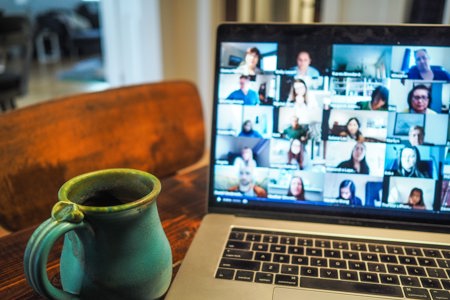 A coffee mug sitting next to an open laptop on a brown wooden table