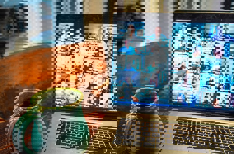 A coffee mug sitting next to an open laptop on a brown wooden table