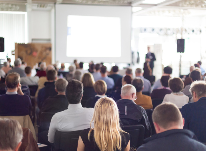 A large room full of people listening to someone talking. 