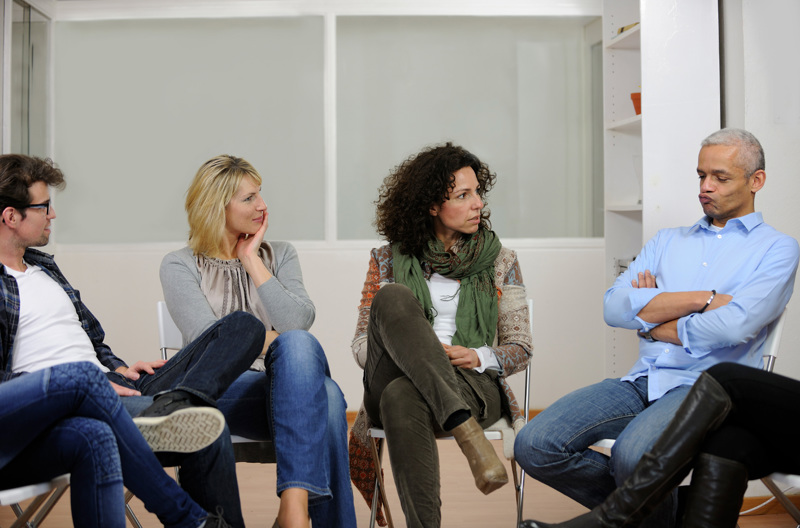 Four people sitting on chairs talking with each other. 