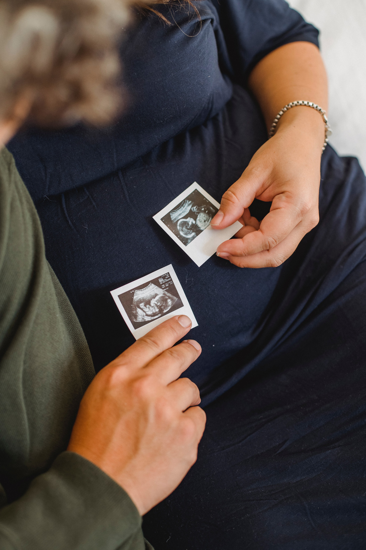 A couple both holding ultrasound images of their unborn child. 