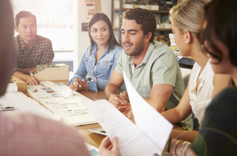 A group of people sitting at a desk working on a project.
