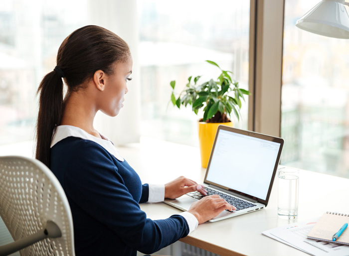 A woman sitting at a desk working on a laptop.