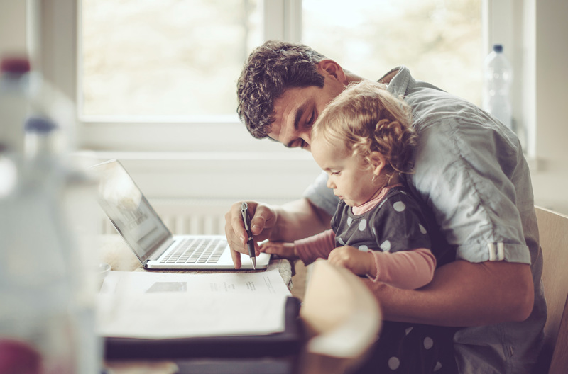 A parent sitting with his child at a table while drawing.