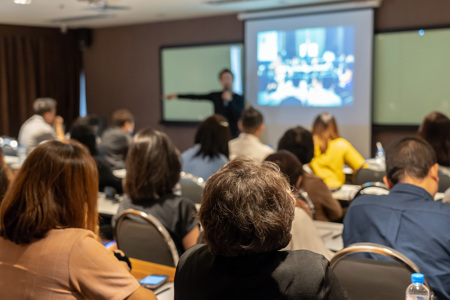 A teacher presenting in front of a classroom full of students. 