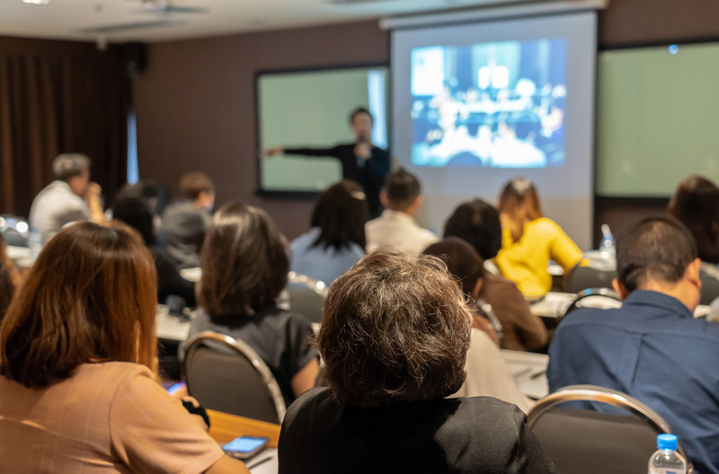 A teacher presenting in front of a classroom full of students. 