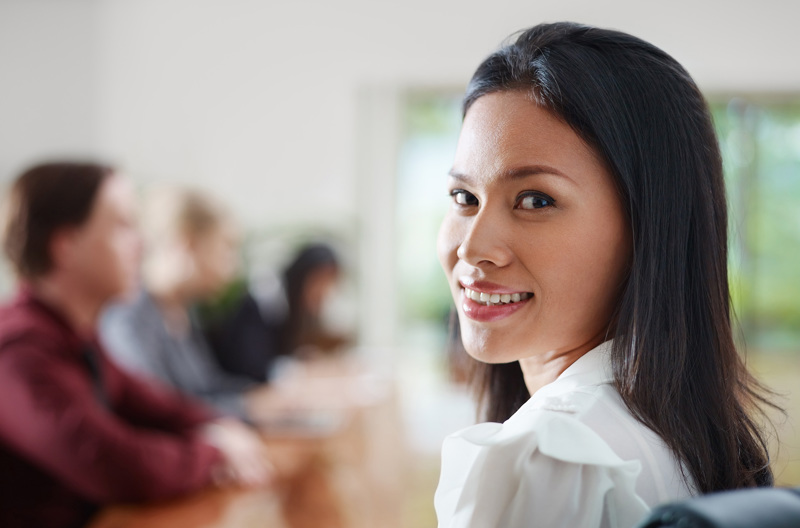 A woman sitting in a chair looking back and smiling.