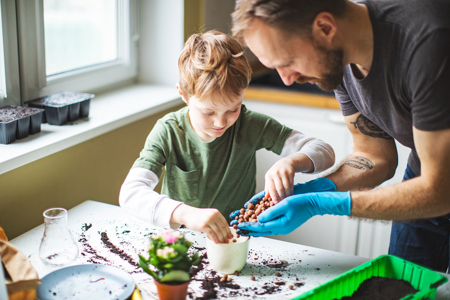 A father potting a plant with his son.