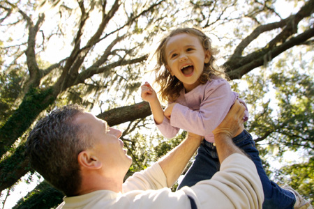 A parent lifting their laughing child above their head.