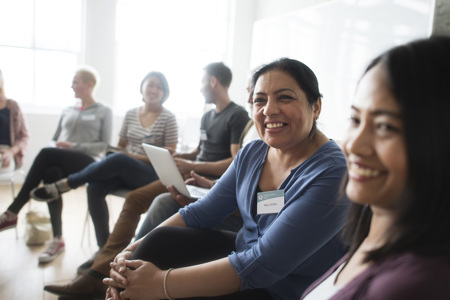 A group of people sitting together in a circle smiling. 