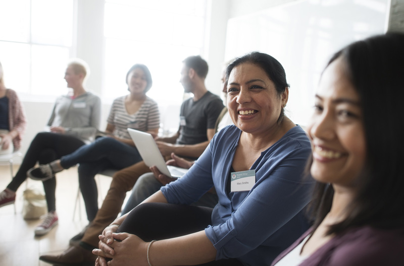 A group of people sitting together in a circle smiling. 