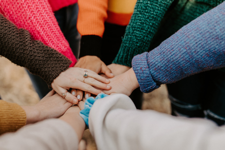 A group of people placing their hands on top of each others. 