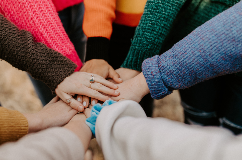 A group of people placing their hands on top of each others. 