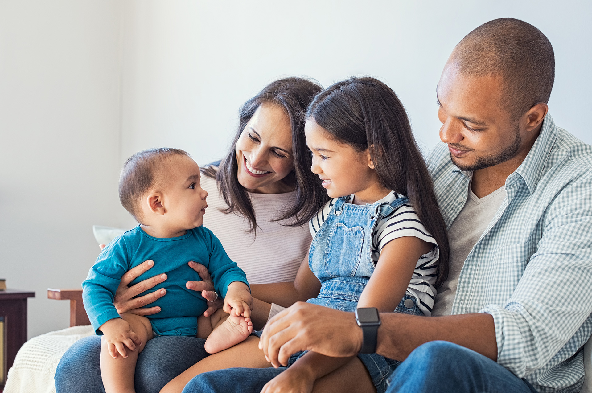 Two parents sitting with their two children on a couch. 