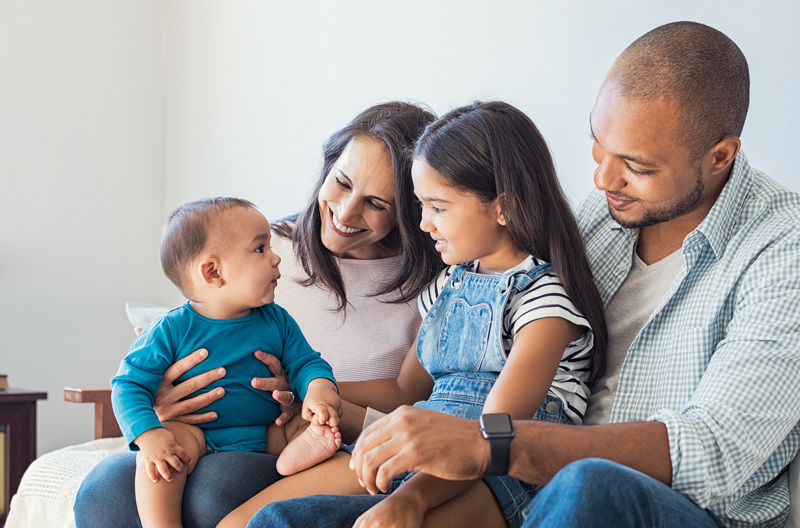 Two parents sitting with their two children on a couch. 