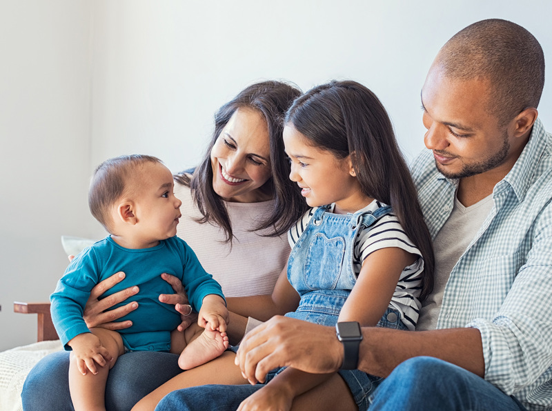 Two parents sitting with their two children on a couch. 