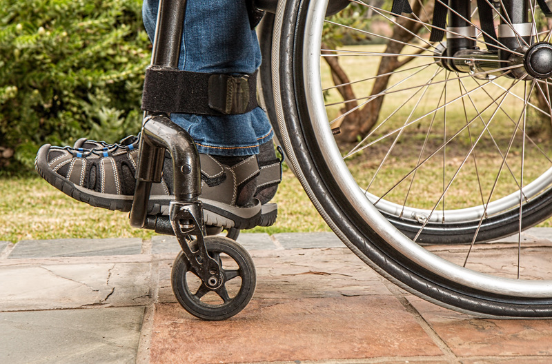 A man wearing sandals while sitting in a wheelchair. 