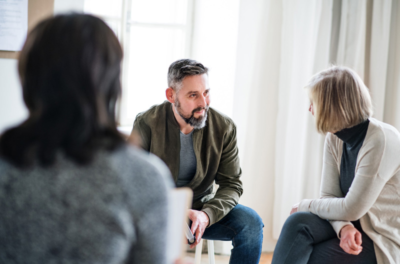 Three people sitting together in a circle talking. 