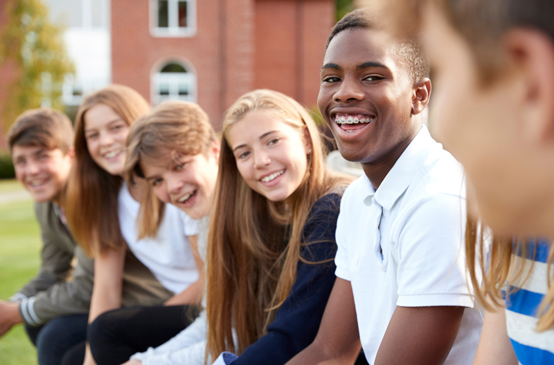 A group of teenagers sitting next to each other smiling.